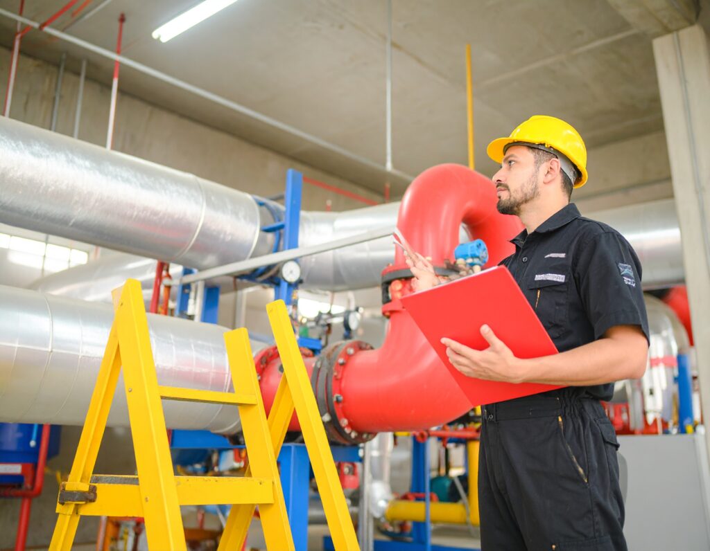 Technician inspecting industrial pipework during HVAC system upgrades.