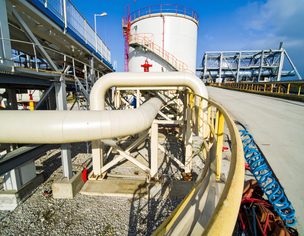 Outdoor industrial gas purging installation with large white pipeline system connected to a storage tank under clear blue sky.