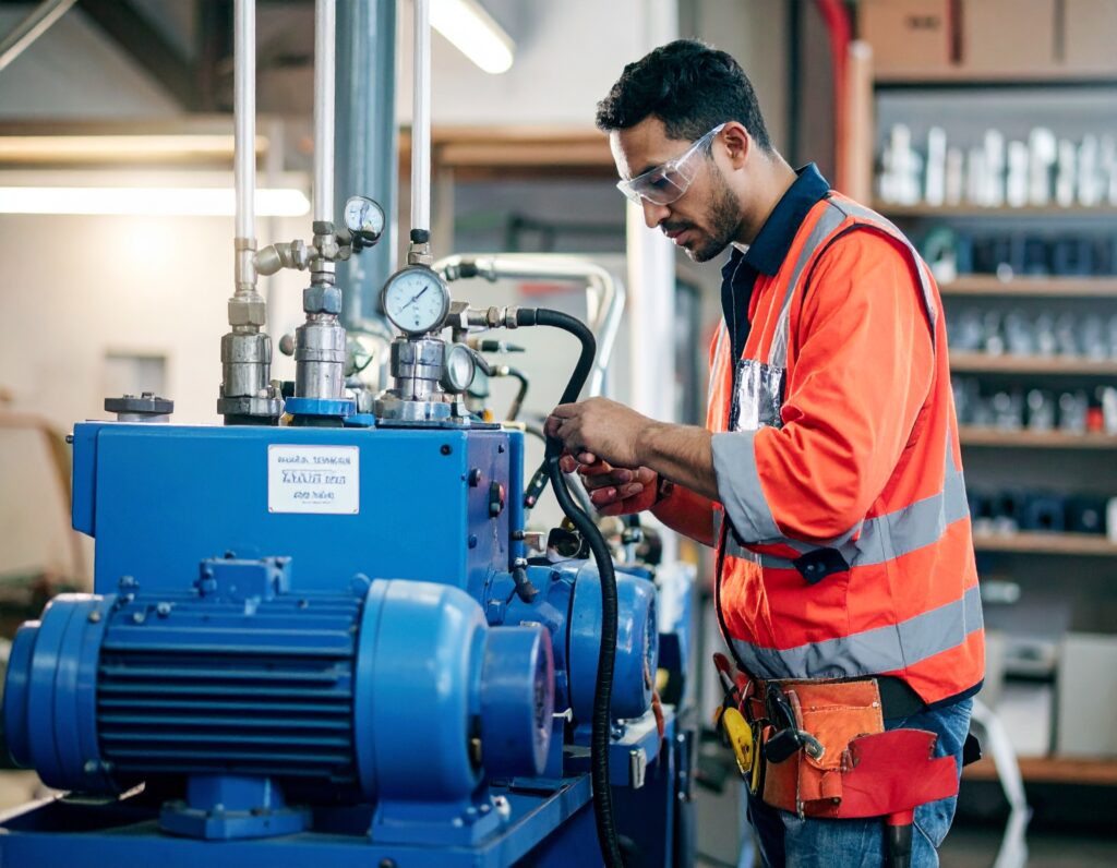 Technician performing initial pressure testing on industrial equipment with gauges and safety gear.