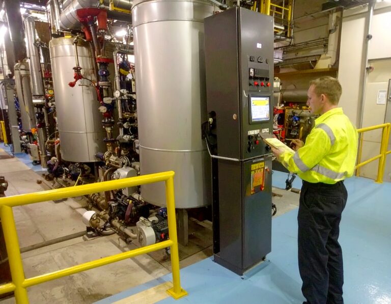 Engineer performing commercial laundry boiler maintenance by inspecting control panel and equipment.
