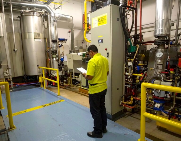 Technician inspecting equipment during laundry boiler repairs in a mechanical room.