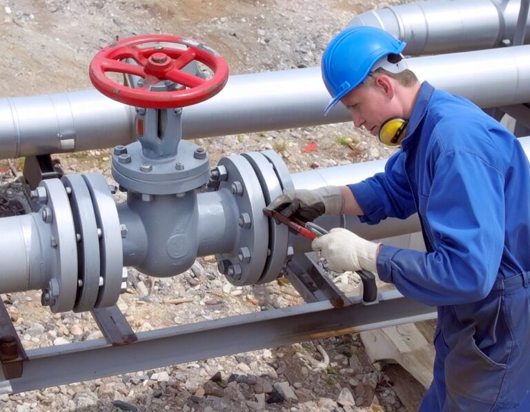 Worker tightening pipeline valve during maintenance, illustrating compliance with gas purging regulations.