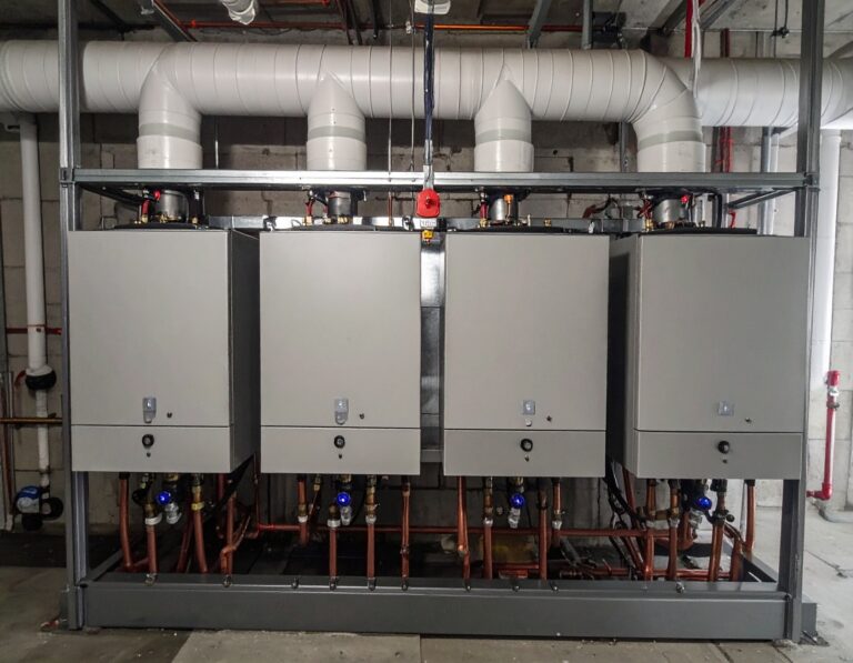 Modern commercial boiler system with upgraded flue pipes and copper connections in a mechanical room.
