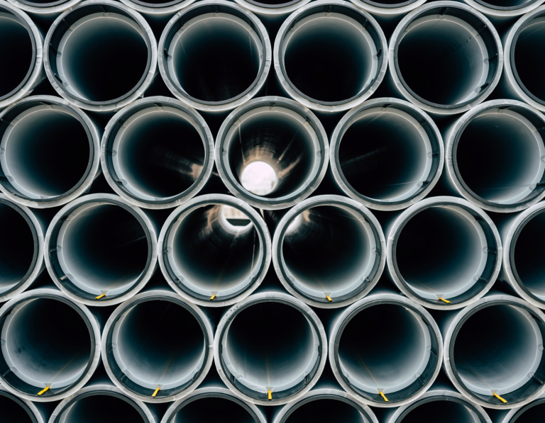 Close-up view of stacked PVC pipework showing uniform circular openings and smooth grey surfaces arranged in neat rows for industrial or plumbing use.